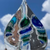 Pyramid Memorial with Cremation Ash in aqua, blue, and green glass shown from side angle outdoors with sky background