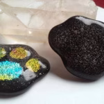 Handcrafted paw print cremation stone made with cremation ash, featuring a memorial glass paw design with shimmering accent colors set into a smooth, rounded keepsake honoring a beloved pet.