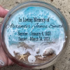 Oceanside Ring Dish with Cremation Ash in a round glass dish featuring ocean wave design, sandy shoreline, seashells, starfish, and personalized memorial text with name and dates