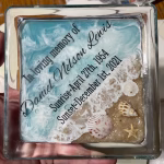 Personalized Oceanside Ring Dish with Cremation Ash featuring a square clear glass memorial dish with engraved name and dates, ocean wave design, sandy shoreline, and embedded seashells