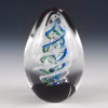 Handcrafted spiral egg-shaped cremation glass keepsake featuring a clear glass form with blue and green spiral detailing and suspended cremation ashes inside.
