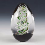 Handcrafted spiral egg-shaped cremation glass keepsake featuring a clear glass form with a green spiral design and suspended cremation ashes inside.