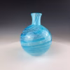 Round aqua glass memorial vase with cremation ash visible inside swirling glass.