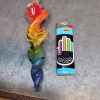 A 6-inch rainbow glass spinner infused with cremation ash, shown next to a blue Bic lighter for size comparison. The spinner features a clear loop at the top and a twisted design with vibrant red, orange, yellow, green, and blue swirls.
