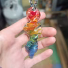 A single 3-inch rainbow glass spinner infused with cremation ash, featuring swirling red, orange, yellow, green, and blue colors, shown resting in a person's hand.