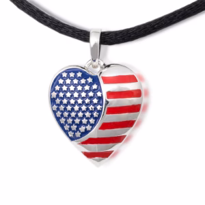 American Flag Cremation Pendant, heart-shaped stainless steel necklace featuring red and white enamel stripes and a blue field of raised silver stars, shown on a black cord against a white background.