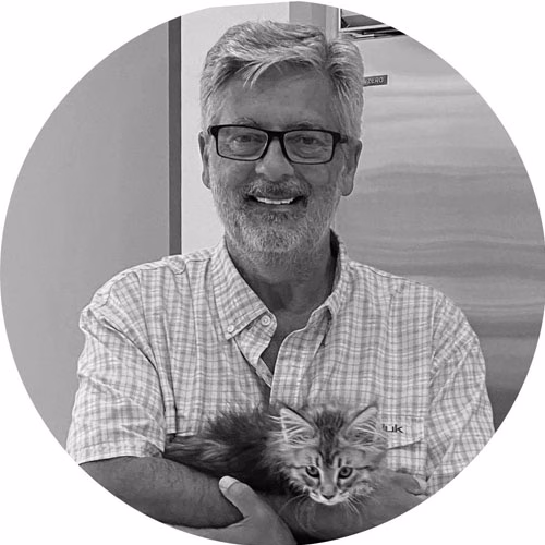 Johan, team member at Sands of Time, holding a kitten and smiling in a black and white portrait