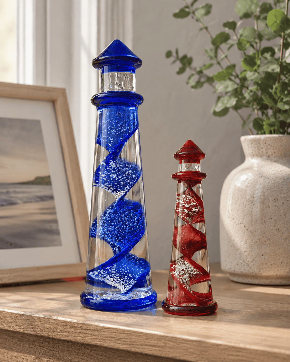 Colorful cremation art glass lighthouses with spiraled design in blue and red.