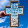 Oceanside cross memorial with ocean-inspired resin waves, embedded seashells, and a Psalm 89:9 scripture overlay, held up against a bright blue sky.