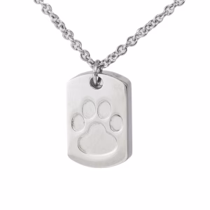 Close-up image of a stainless steel dog tag–style cremation pendant featuring an engraved paw print design on the front.