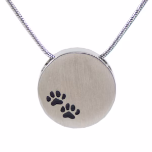 Pewter round cremation necklace with two small black paw print engravings on the front, shown on a silver chain against a white background