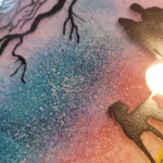 Close-up view of the Family Dog Walk Cremation Sun Plate, showing textured cremation ash embedded in a colorful gradient background with silhouetted figures and tree branches.