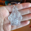 Clear glass paw print cremation pendant with visible encased cremation ash shown resting in the palm of a hand on a silver ball chain