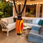 Hearthwood urn pendant in yellow and red wood with black stainless steel core hanging from a braided cord in an indoor living space
