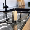 Hearthwood urn pendant in holly wood with black stainless steel core standing on dark marble countertop with black chain beside modern kitchen sink
