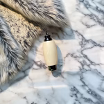 Hearthwood urn pendant in holly wood with black stainless steel core resting on white marble surface beside soft gray fur
