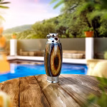 Hearthwood urn pendant with mountain camo wood grain pattern and stainless steel core standing upright on a wooden table outdoors, straight-on view