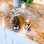 Hearthwood urn pendant with mountain camo wood and stainless steel core shown open with threaded lid on marble countertop with silver chain attached