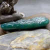 Side view of glass paw print cremation pendant in blended teal and green glass with encased cremation ash resting on stone background