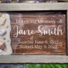Oceanside memorial plaque with seashells and a sandy shoreline on the left, and a wooden-style panel on the right engraved with “In Loving Memory of Jane Smith, Sunrise June 6, 1933, Sunset May 9, 2021.”