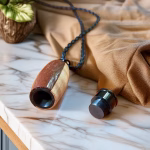 Hearthwood urn pendant in black walnut and maple wood with black stainless steel core shown open on a marble surface with braided cord and detached screw top