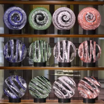 Glass ribbon marbles with cremation ash displayed in a glass showcase, featuring spiral and striped patterns in blue, green, pink, and red