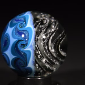 Handmade Shadow Marble with Cremation Ash featuring black glass with blue pinwheel backing