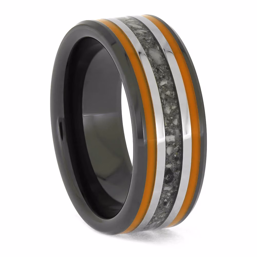 Angled view of black ceramic memorial ring with orange enamel pinstripes and titanium inlay band containing cremation ashes.