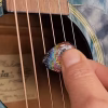 Functional Glass Guitar Pick with Cremation Ash being used on acoustic guitar strings during play
