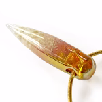 Angled side view of a solid glass crystal cremation pendant featuring a clear-to-amber gradient created with pure gold fume, suspended from a gold snake chain for holding cremation ashes.