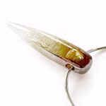 Angled side view of a solid glass crystal cremation pendant featuring a clear-to-amber gradient created with pure silver fume, suspended from a silver snake chain for holding cremation ashes.