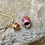 Angled top view of an opened extra small royal honey acrylic urn pendant with a gold-colored stainless steel core, showing the threaded interior and detached gold cap attached to a snake chain for holding cremation ashes.