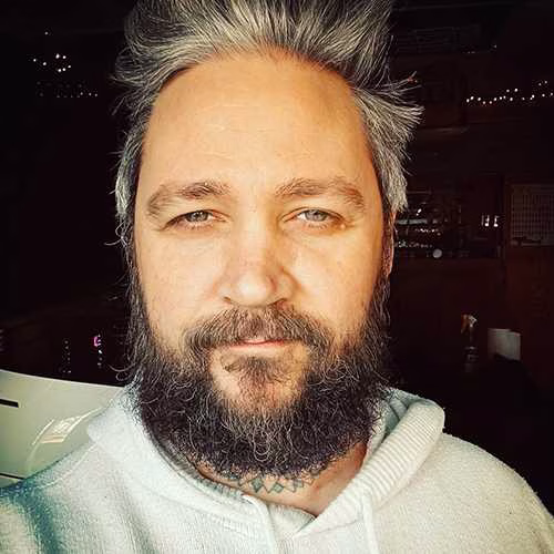 Portrait of the founder of Sands of Time wearing a light hoodie in a studio setting