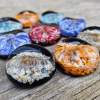Comfort Stones with Cremation Ash displayed in multiple vibrant color variations arranged on a rustic wooden surface, by Sands of Time.