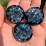 Comfort Stone with Cremation Ash shown in three blue glass variations held in hand for size reference, by Sands of Time.