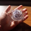 Memorial glass flower being held in hand showing purple glass tones and cremation ash suspended inside, by Sands of Time.