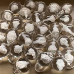 Multiple Heaven Drop memorial glass pieces displayed on a wooden surface with cremation ash suspended inside, by Sands of Time.