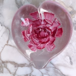 Glass Heart of Remembrance displayed on a marble countertop with pink memorial glass and cremation ash suspended inside, by Sands of Time.