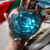 Glass Heart of Remembrance being held in hand showing size and cremation ash suspended inside the blue glass, by Sands of Time.