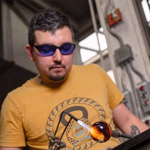 Glass artist working with a torch while shaping memorial glass in the studio, by Sands of Time.