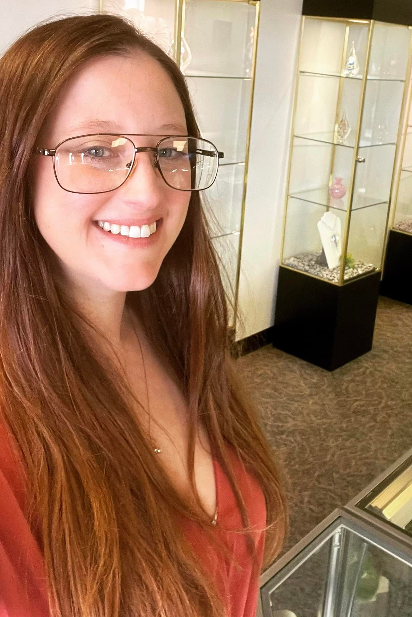 Inside the memorial art showroom with illuminated display towers and memorial jewelry exhibits behind a smiling team member