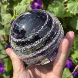 Amethyst birthstone glass paperweight with cremation ashes showing the Sparkle Swirl pattern and deep purple glass in natural light