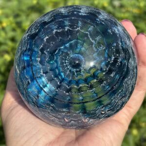 Top view of an aquamarine birthstone glass paperweight with cremation ashes and a layered Ripple Vortex pattern in blue and aqua glass