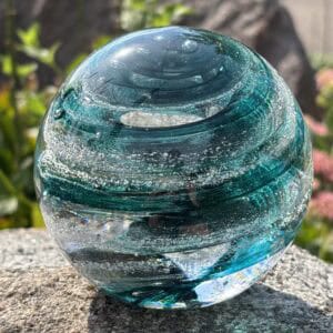 Front view of blue tourmaline birthstone glass paperweight with cremation ashes in a Sparkle Swirl design