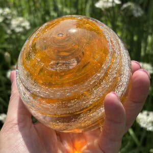 Top view of citrine birthstone glass paperweight with cremation ashes and gold sparkle in a Gold Sparkle Swirl design