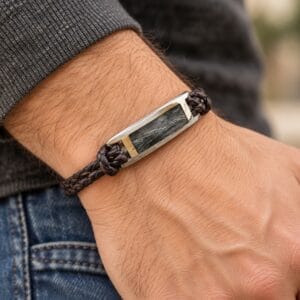 Hair or fur memorial bracelet with a braided leather band and stainless steel centerpiece worn on a wrist