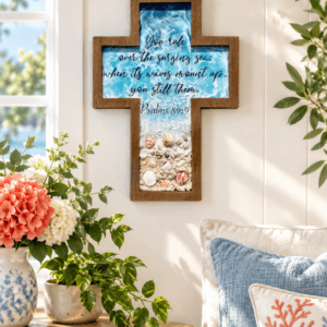 Oceanside memorial wall cross with cremation ashes displayed in a bright living space above a side table with fresh flowers and coastal decor.