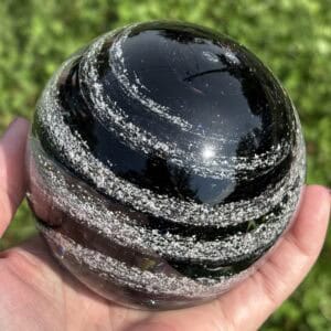 Handheld angled view of onyx glass paperweight with cremation ashes in a Sparkle Swirl design