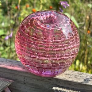 Front view of pink topaz birthstone glass paperweight with cremation ashes in a Ripple Vortex design