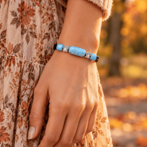 Woman wearing a sky blue paw print pet cremation bracelet with ashes and silver-toned paw print accents in a fall setting